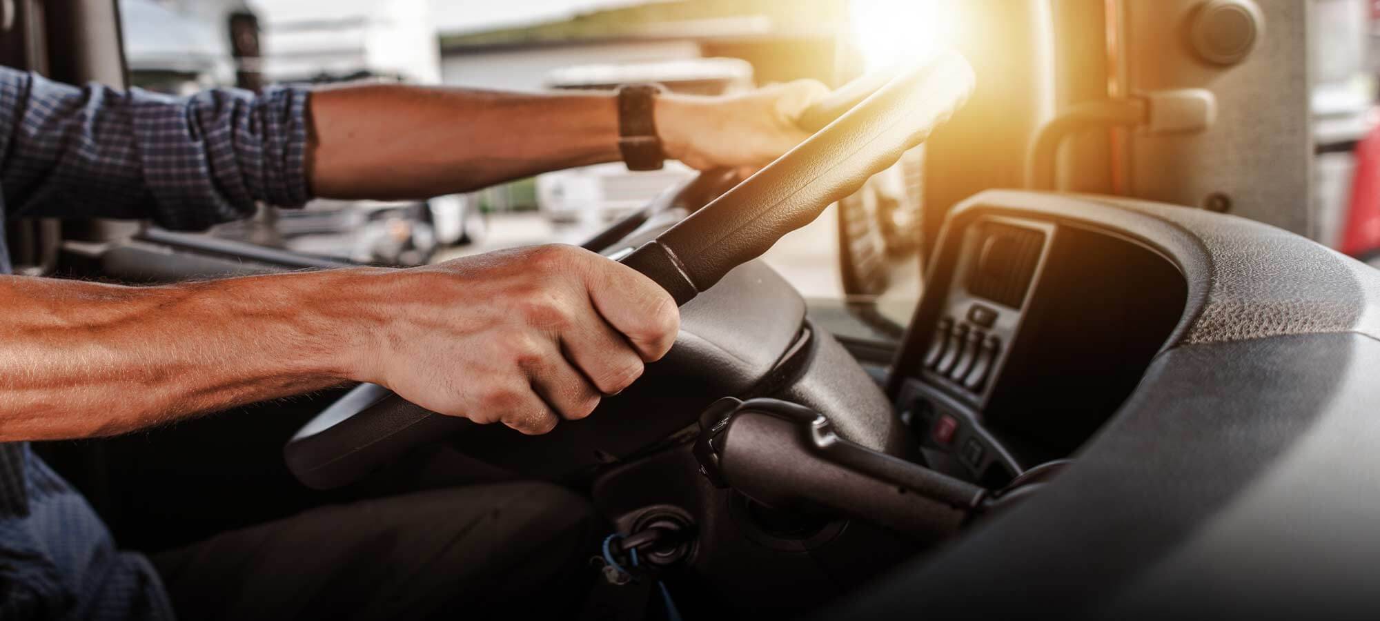 Close up photo of a truck drivers hands on the steering wheel of a semi tractor