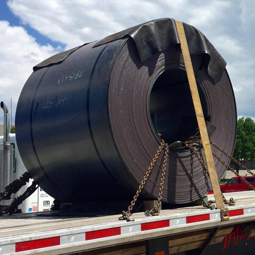 Large roll of sheet steel secured on a flatbed trailer for hauling