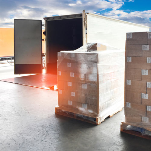 Dry van trailer sitting in a loading dock waited to be loaded with nearby palletized product